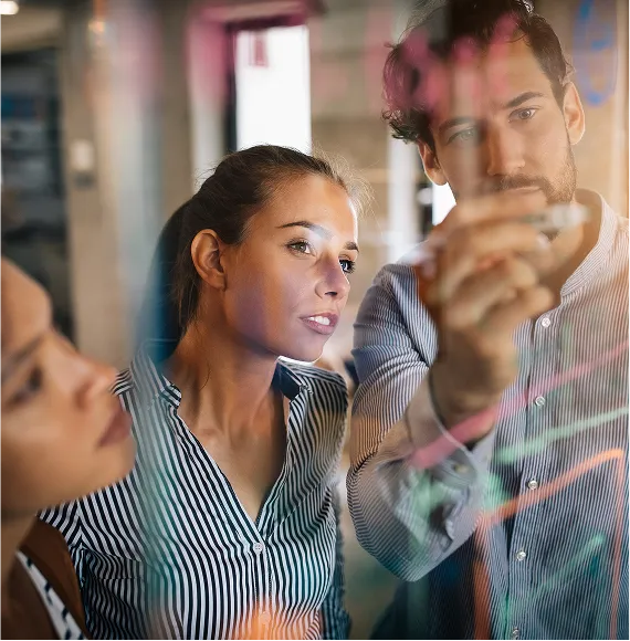 Group engaged in creative brainstorming in front of a glass panel in a modern office; focus on collaboration, analysis, and strategic thinking.