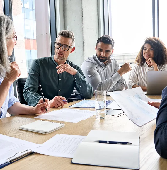 Business meeting in a bright office environment with several people in conversation; focus on team communication, planning, and strategic collaboration.