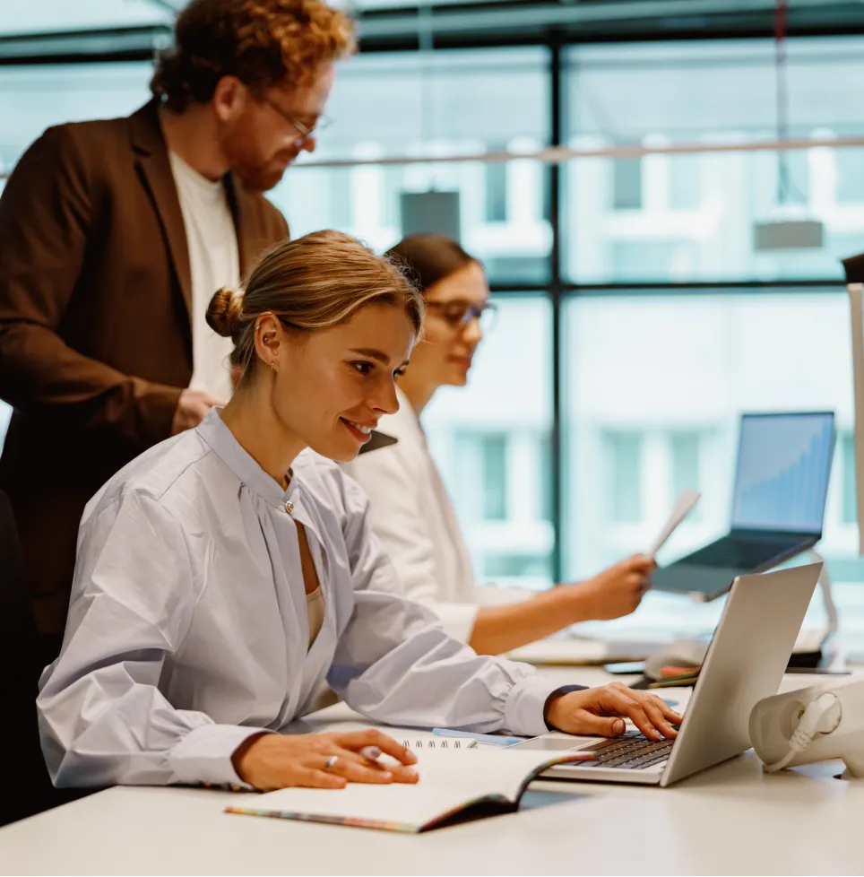 Team works concentrated on laptops and documents in a modern office; focus on digital collaboration, project work and a productive working environment.